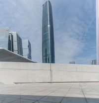 a young boy skateboards on a sidewalk in front of a modern city building, with tall buildings