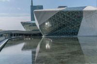 a large modern building that is in water with people standing around it outside a city square