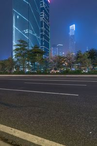 a city street with buildings and neon lights at night time in hong china as seen from an empty city highway