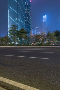 a city street with buildings and neon lights at night time in hong china as seen from an empty city highway