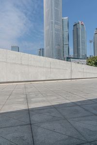 a boy is skateboarding on the edge of the sidewalk in a city square with highrise buildings