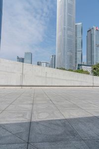 a boy is skateboarding on the edge of the sidewalk in a city square with highrise buildings