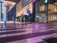 rainy street in urban area with building and trees near intersection of crosswalks at night