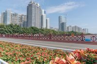 view on a bridge that leads to several buildings over a lake with flowers in front