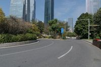 the empty road is lined with buildings and plants on either side of it, in the middle of the city