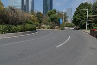 the empty road is lined with buildings and plants on either side of it, in the middle of the city