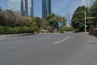 the empty road is lined with buildings and plants on either side of it, in the middle of the city