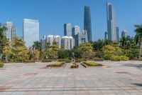 a park with a bench and large statue on the top of the concrete ground, with tall buildings in the back