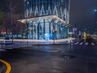 a street scene looking at a bus stop on a city street at night with lights on