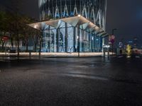 a street scene looking at a bus stop on a city street at night with lights on