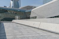 a man on a skateboard in an empty walkway near the cityscape of tall buildings