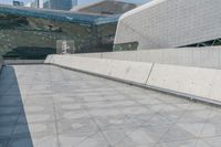 a man on a skateboard in an empty walkway near the cityscape of tall buildings