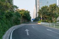 two white arrows are going in opposite directions on an empty road with tall buildings in the background