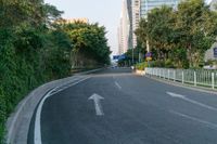 two white arrows are going in opposite directions on an empty road with tall buildings in the background