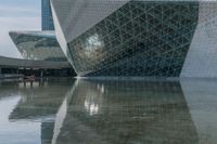 a large glass building is reflected in the water below it's glassy facade