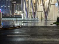 street signs in front of a very tall building at night on a wet city street