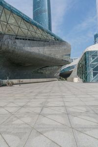 a person riding a skateboard across a cement plaza next to buildings and skylights