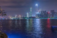 a city street with buildings and neon lights at night time in hong china as seen from an empty city highway