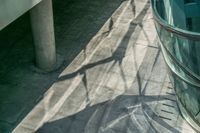 a long shadow of a person walking down a walkway as a large clock hangs above them