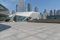 the building has glass and a steel structure in front of it, and several skyscrapers in the background