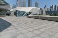 the building has glass and a steel structure in front of it, and several skyscrapers in the background