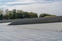 a person on a skateboard in an urban park next to concrete walls and trees