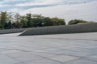 a person on a skateboard in an urban park next to concrete walls and trees