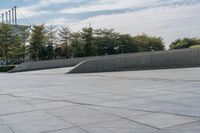 a person on a skateboard in an urban park next to concrete walls and trees