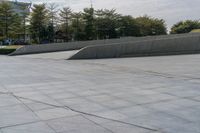 a person on a skateboard in an urban park next to concrete walls and trees