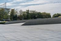 a person on a skateboard in an urban park next to concrete walls and trees