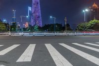 a city street with buildings and neon lights at night time in hong china as seen from an empty city highway