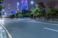 a city street with buildings and neon lights at night time in hong china as seen from an empty city highway