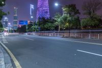 a city street with buildings and neon lights at night time in hong china as seen from an empty city highway