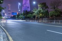 a city street with buildings and neon lights at night time in hong china as seen from an empty city highway