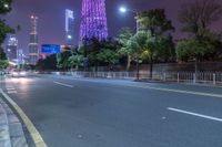 a city street with buildings and neon lights at night time in hong china as seen from an empty city highway