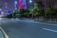 a city street with buildings and neon lights at night time in hong china as seen from an empty city highway