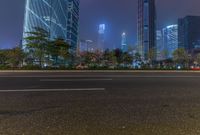 a city street with buildings and neon lights at night time in hong china as seen from an empty city highway