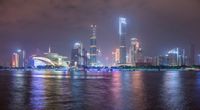 a city street with buildings and neon lights at night time in hong china as seen from an empty city highway