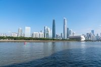 the skyline of a city rises behind the water of a river and boats on the water