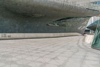 a man walks down the road in front of a large building with some glass walls