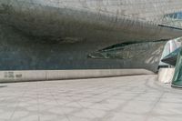 a man walks down the road in front of a large building with some glass walls