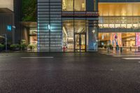 an empty street in a city at night time with people crossing the street and buildings at both sides