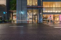 an empty street in a city at night time with people crossing the street and buildings at both sides