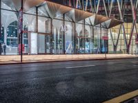 an outside bus station is illuminated at night time with rain falling down the walkway and lights shining on the outside