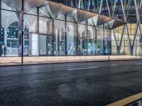 an outside bus station is illuminated at night time with rain falling down the walkway and lights shining on the outside