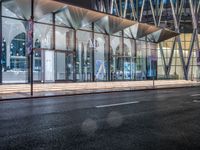 an outside bus station is illuminated at night time with rain falling down the walkway and lights shining on the outside