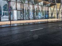 an outside bus station is illuminated at night time with rain falling down the walkway and lights shining on the outside