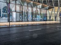 an outside bus station is illuminated at night time with rain falling down the walkway and lights shining on the outside