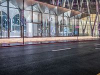 an outside bus station is illuminated at night time with rain falling down the walkway and lights shining on the outside