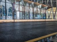 an outside bus station is illuminated at night time with rain falling down the walkway and lights shining on the outside